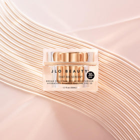 JLO BEAUTY tube beside hand showing 1.7 fl oz size and scale
