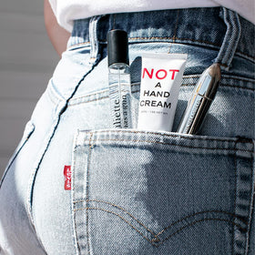 Juliette Has A Gun 1 oz tube next to a wallet for scale showing portable size