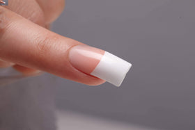 KISS applied on model hand demonstrating long-length nude French nails for elegant look