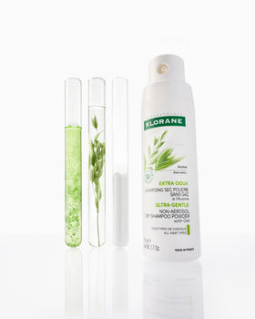 Klorane bottle size comparison beside sunglasses and passport to show travel ease