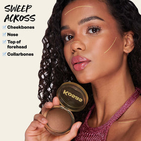 Kosas brush swipe across bronzer demonstrating smooth application