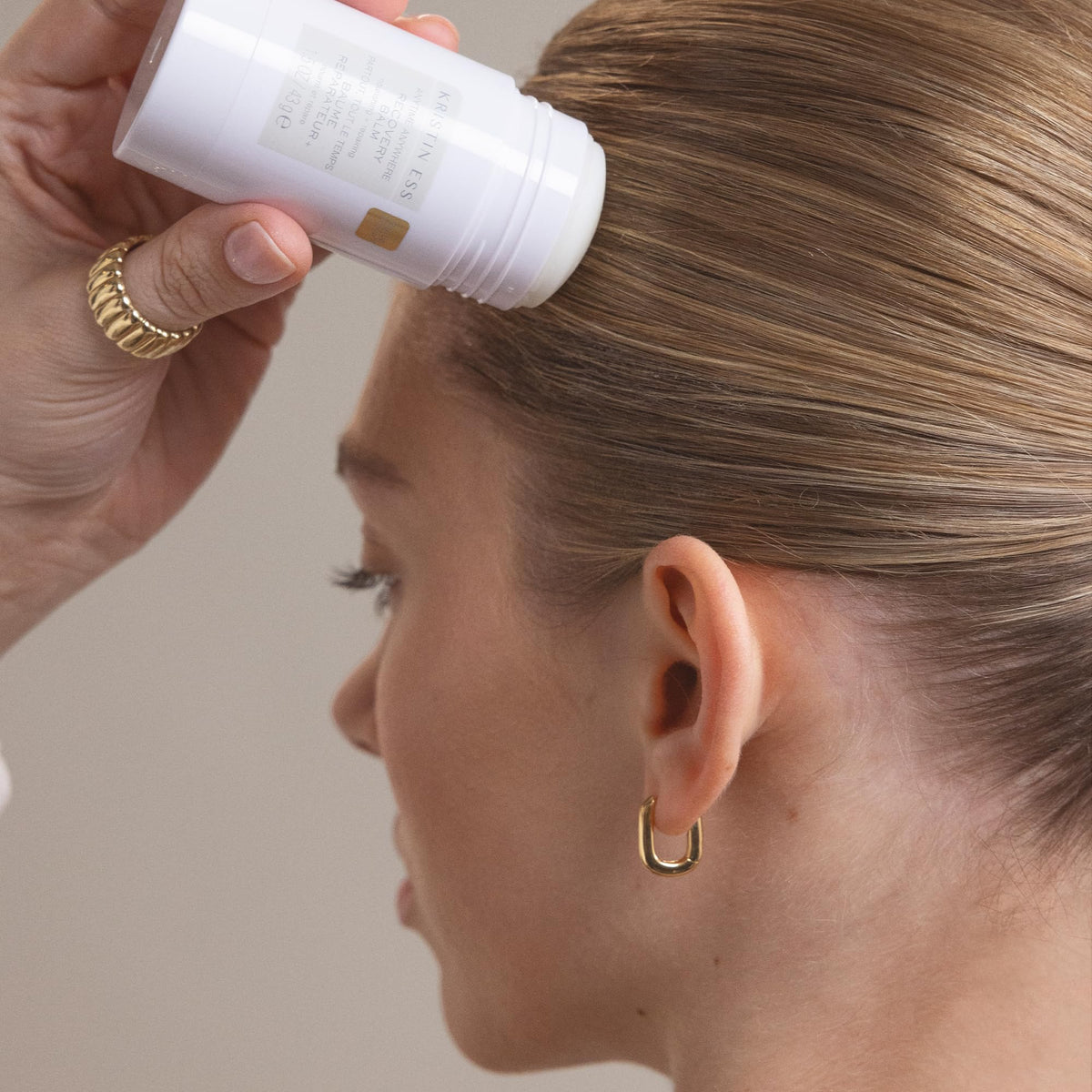 Kristin Ess balm being applied to edges for sleek control and frizz reduction