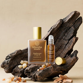 Kuumba Made bottle staged with candles suggesting warm, ritual ambiance