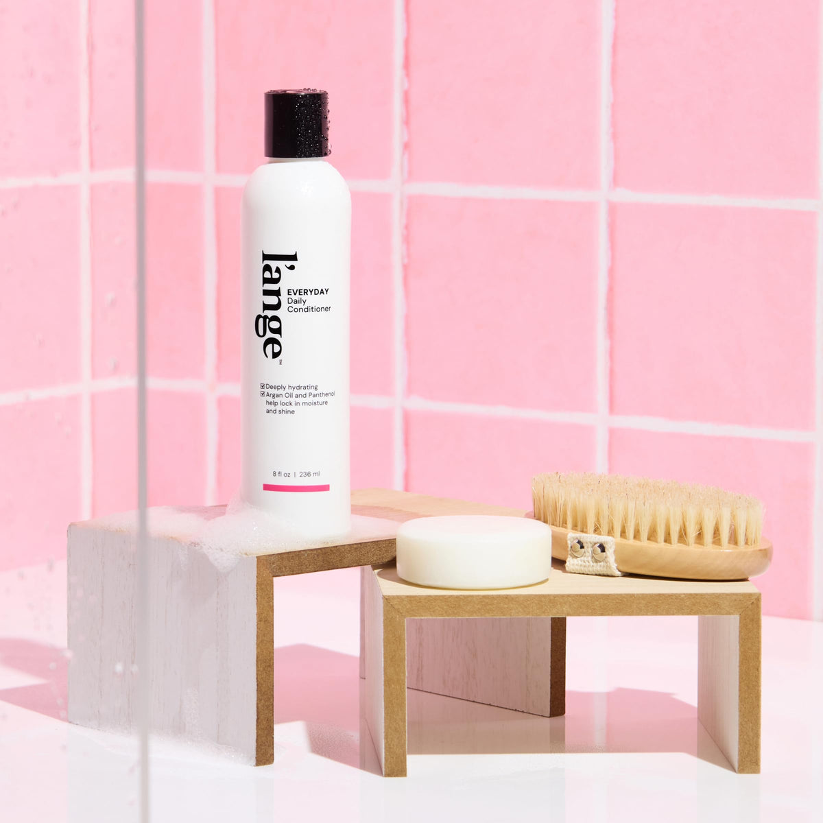 L'ANGE HAIR conditioner on bathroom shelf in lifestyle scene showing routine fit