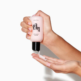 L'ANGE HAIR 4 fl oz tube next to a hand for size and portability