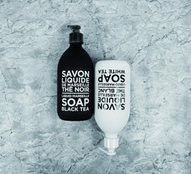 La Compagnie de Provence bottle next to hand for scale, illustrating compact 10 fl oz size and refillable design