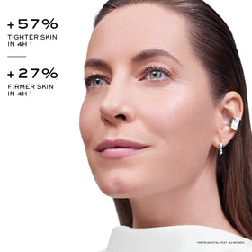 Lancôme woman applying cream in mirror portraying daily routine and smoother-looking contours