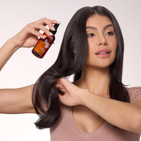 L'ANGE HAIR bottle beside hairbrush demonstrating compact size and daily convenience