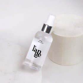 Jojoba and safflower oils near L'ANGE HAIR bottle highlighting nourishing ingredients