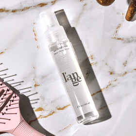 L'ANGE HAIR bottle next to passport showing travel-ready convenience