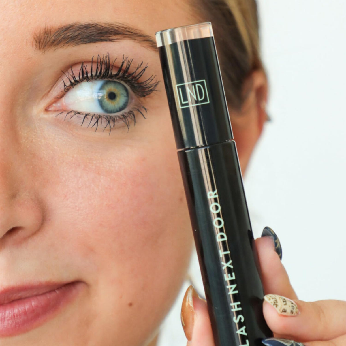 Lash Next Door on model applying mascara in lifestyle setting for real-use inspiration