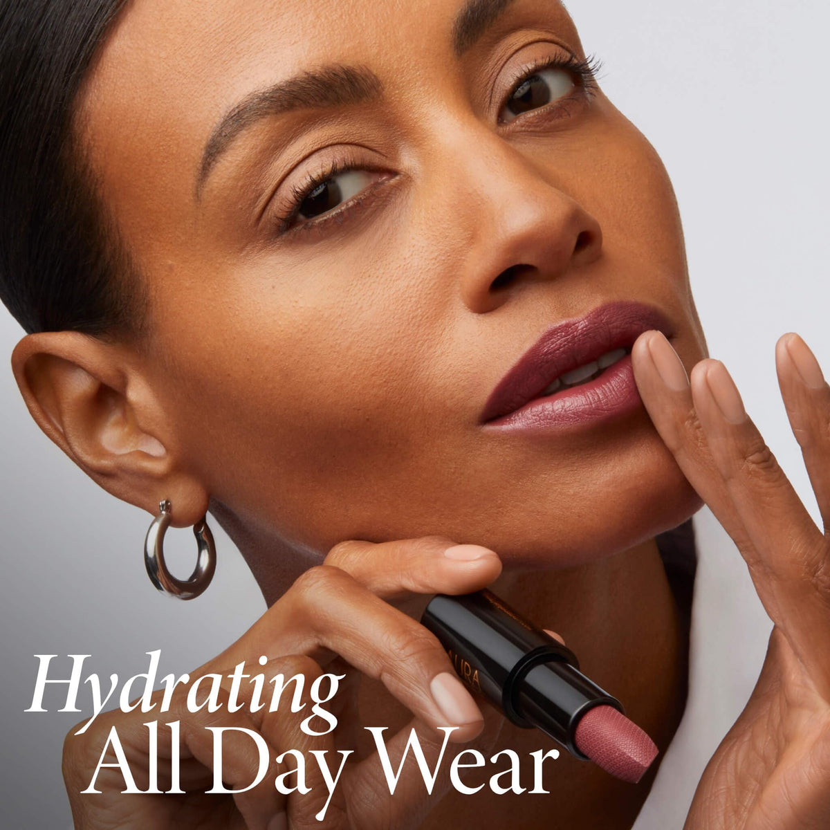 LAURA GELLER NEW YORK lipstick held in hand showing size and portability for on-the-go use