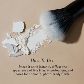 Laura Geller powder being picked up by brush for easy mattifying application