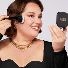 Laura Geller compact beside coin to show compact size and travel convenience