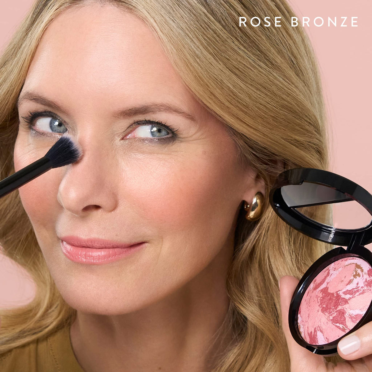 LAURA GELLER brush picking up powder to show effortless two-in-one application