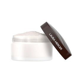 Laura Mercier compact inside makeup bag near mirror suggesting on-the-go touchups