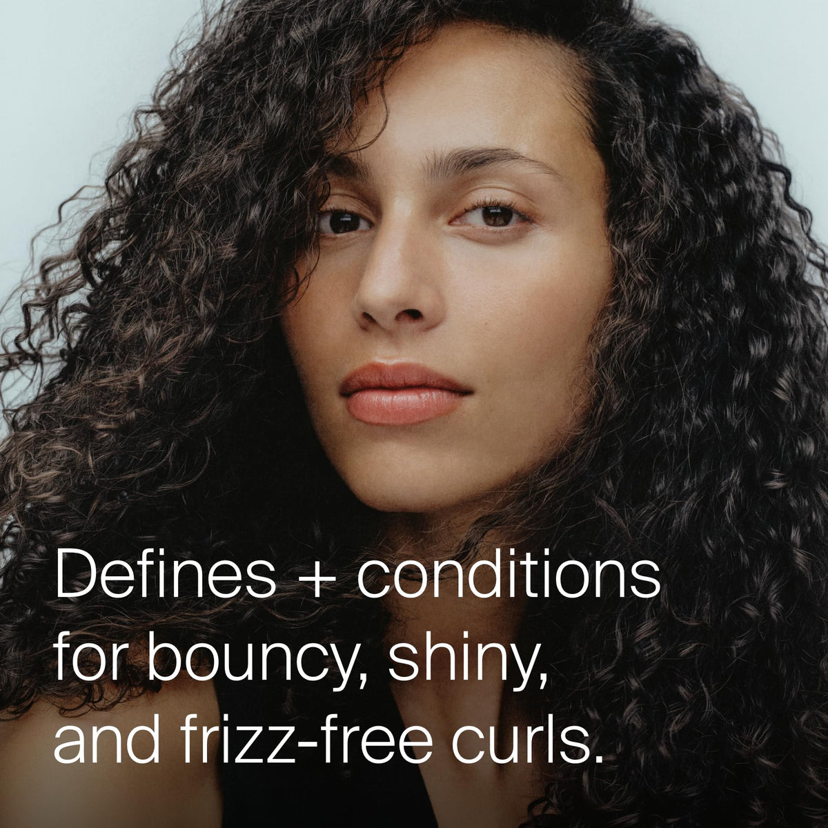 Living Proof applying product to damp hair for even curl definition