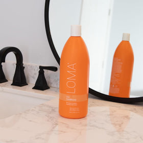 Loma bottle beside tangerine orange grapefruit highlighting natural aroma