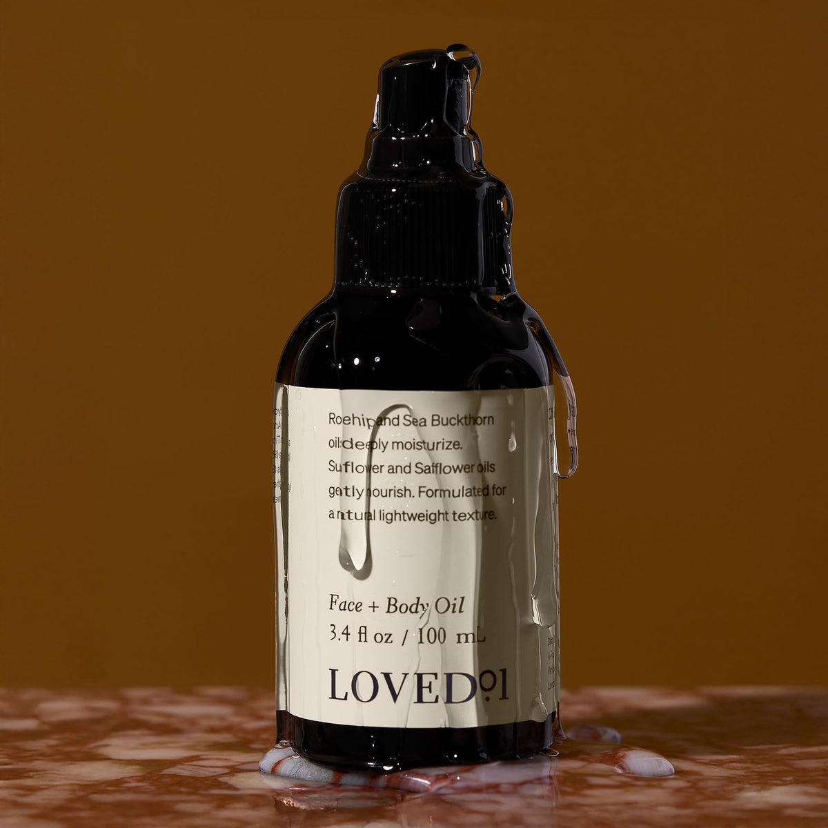 Loved01 bottle next to hand showing 3.4 oz size and portability