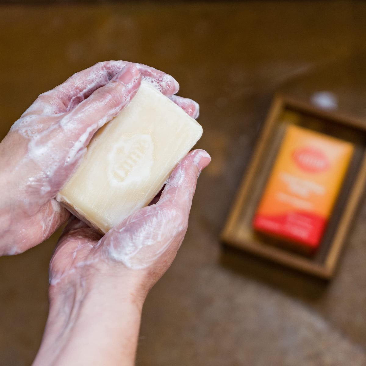 Lume Clean Tangerine bar resting in a draining soap dish to show recommended storage for extended lifespan