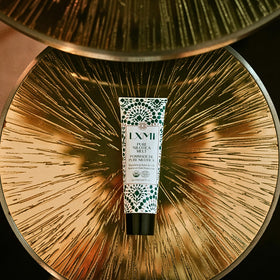 LXMI size comparison next to a coin illustrating compact travel-friendly tube