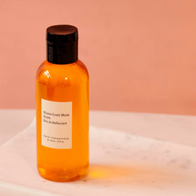 Maison Louis Marie bottle beside everyday objects showing 118 ml scale for travel-friendly size