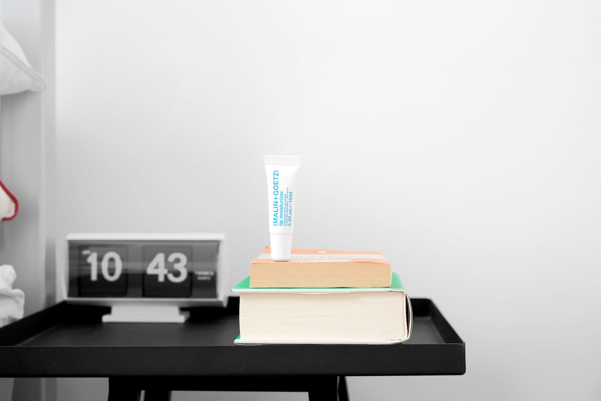 MALIN+GOETZ application on lips in lifestyle setting for long-lasting comfort benefit