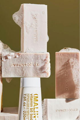 MALIN+GOETZ bar beside shea butter and hyaluronic vial, highlighting nourishing ingredients