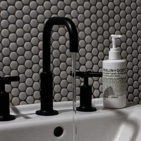 MALIN+GOETZ bottle on shower shelf lifestyle scene suggesting daily ritual relaxation benefit