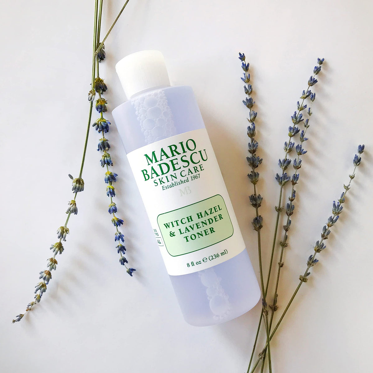 Mario Badescu 8 fl oz bottle in hand showing true size and travel suitability