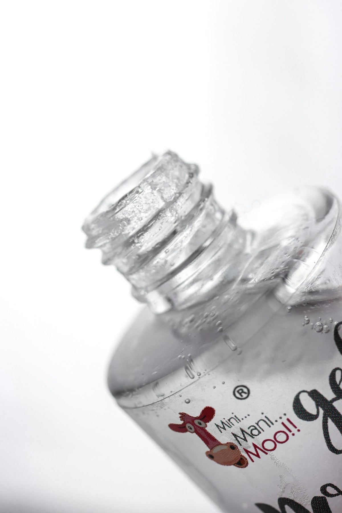 MINI MANI MOO bottle beside a hand for scale showing travel-friendly 10 mL size