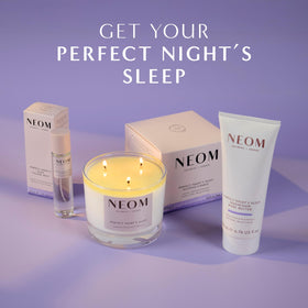 Neom body butter on a bedside table to create a relaxing nighttime routine scene