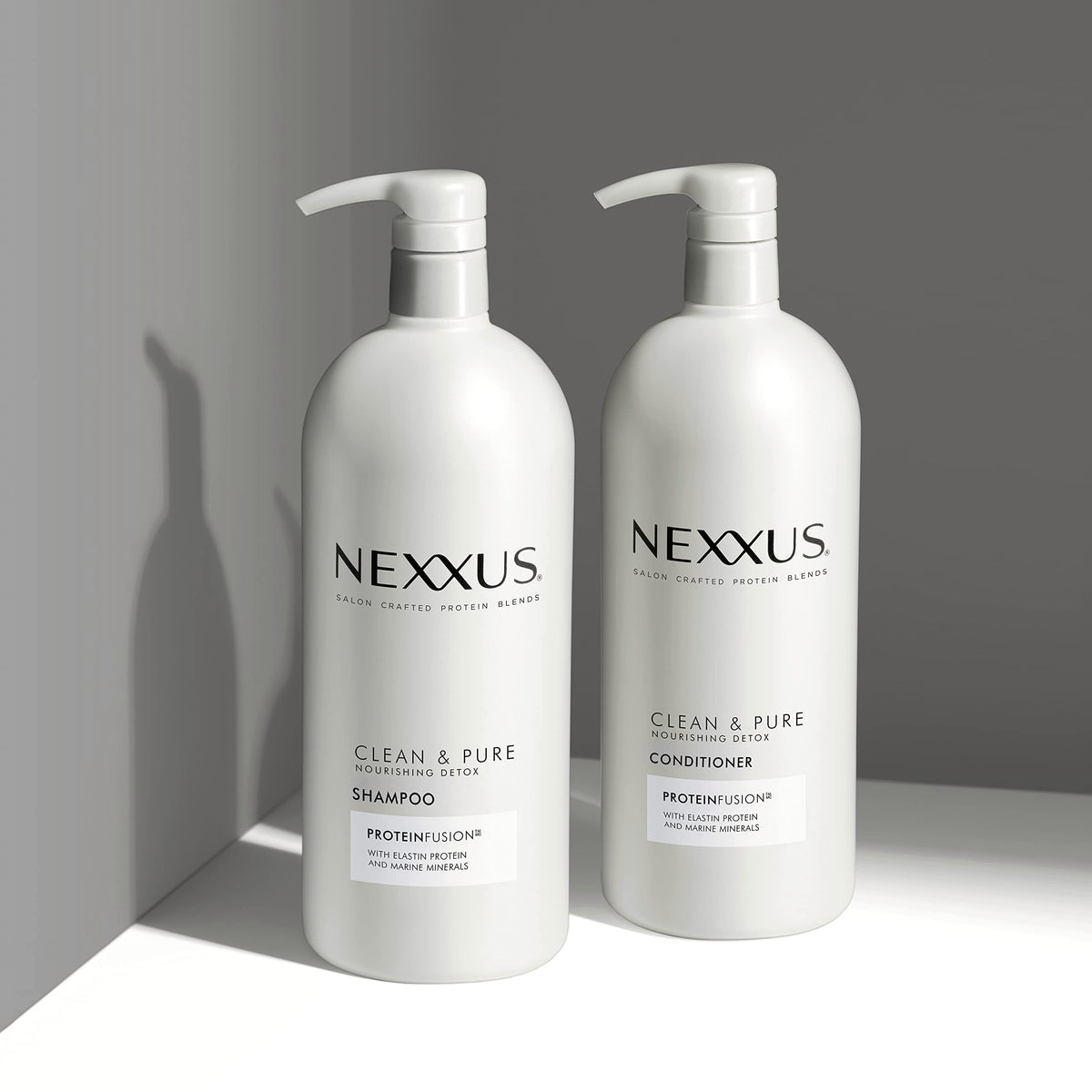 Nexxus 33.8 oz bottles beside a hand for size comparison