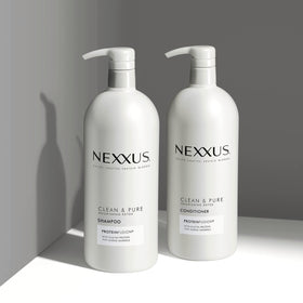 Nexxus 33.8 oz bottles beside a hand for size comparison