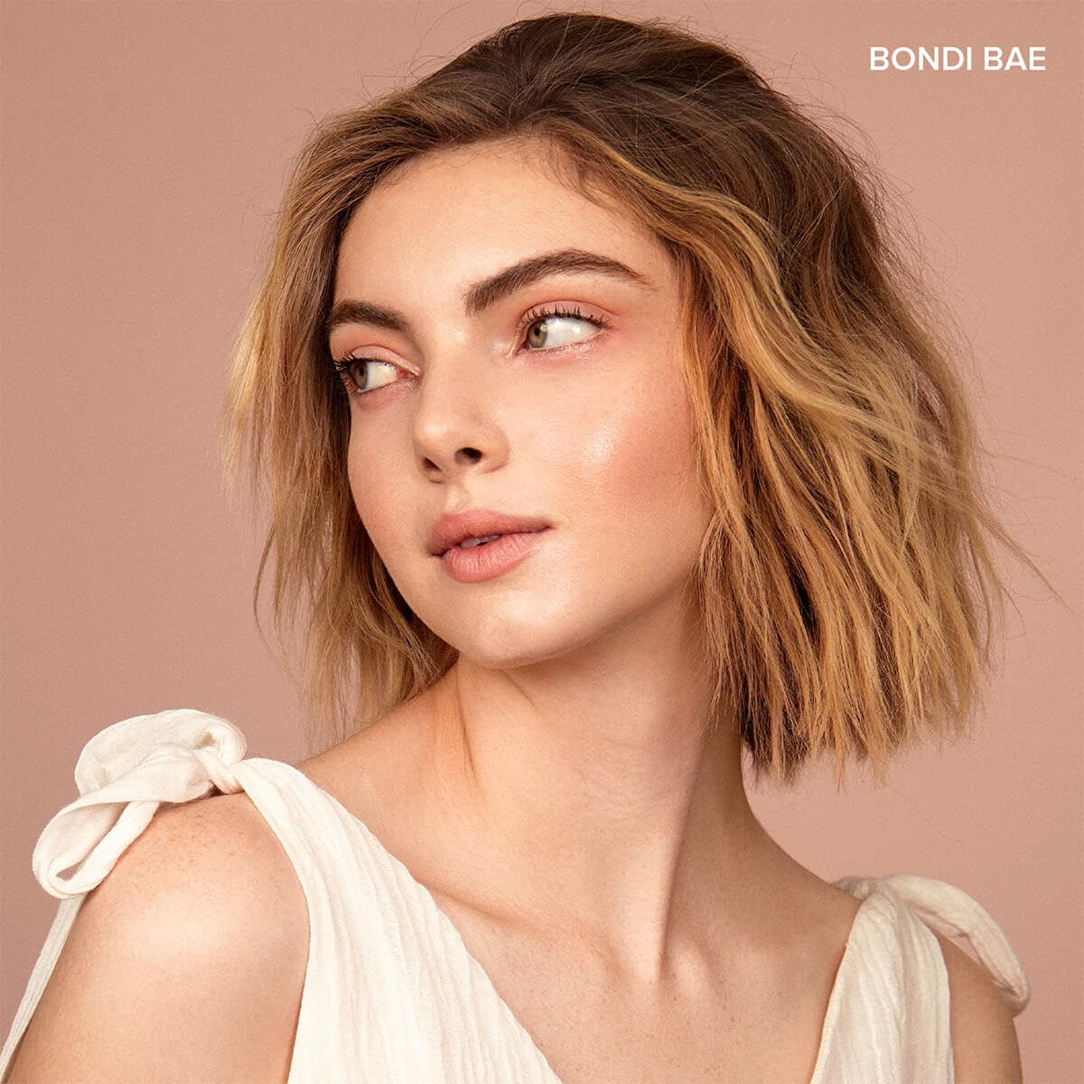 Model applying Nudestix sticks to cheeks and lips demonstrating multi-use convenience