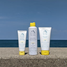 Oars + Alps sunscreen next to a hand for size comparison highlighting portable 6oz travel convenience