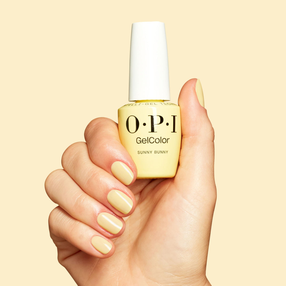 OPI Sunny Bunny bottle next to a hand for accurate size comparison