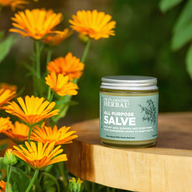 Ora's Amazing Herbal salve on a gardener's hands in outdoor setting showing hardworking skin care benefit