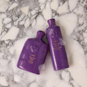 Oribe bottle on bathroom shelf styled with towels showing premium routine benefit