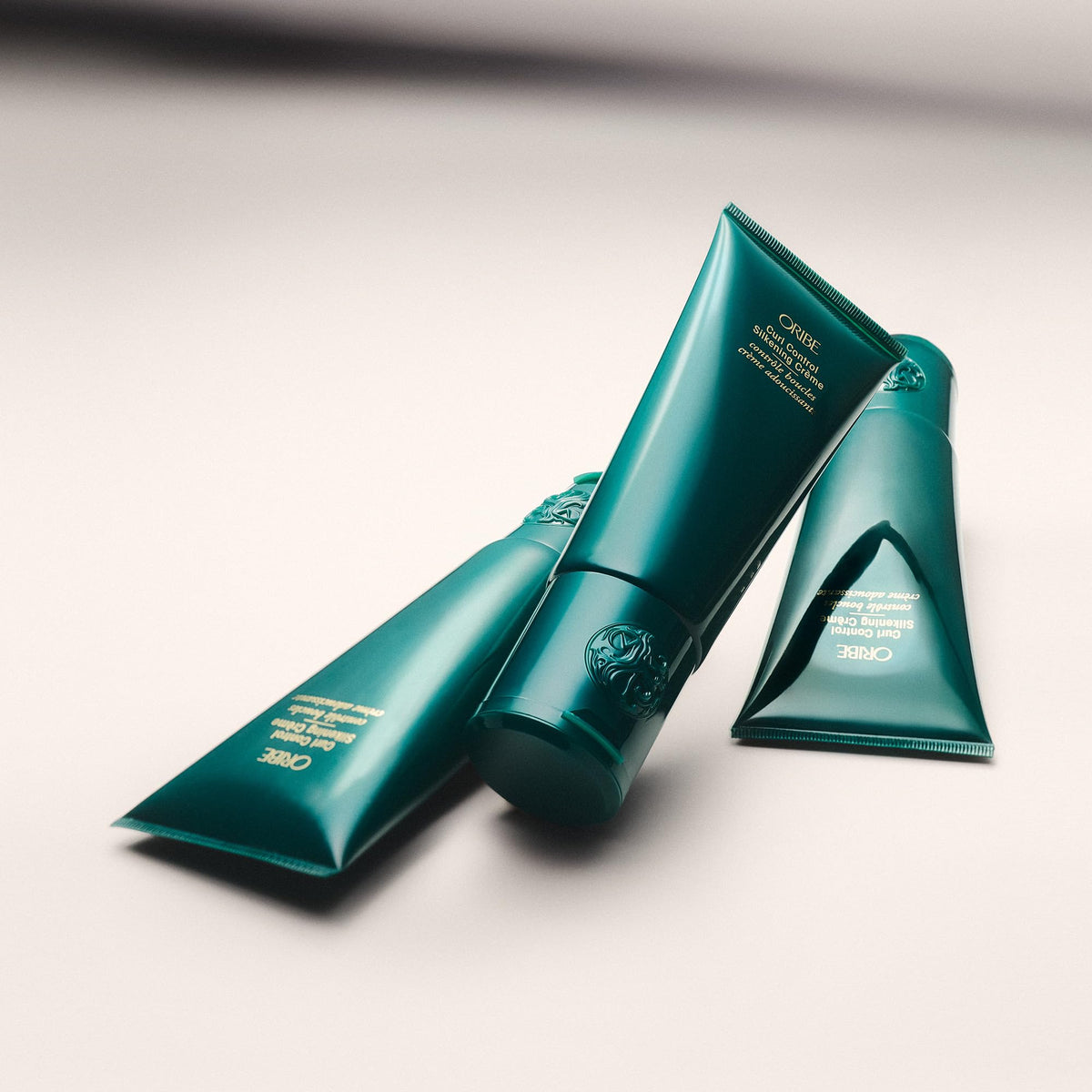 ORIBE applying cream to damp wavy hair to define and tame frizz