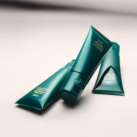 ORIBE applying cream to damp wavy hair to define and tame frizz