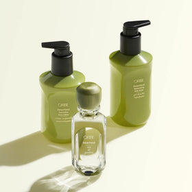 ORIBE bottle beside towel showing 10.1oz size and travel-friendly benefit