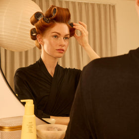 Vanity scene with Oribe balm placed among hair tools illustrating daily styling ritual