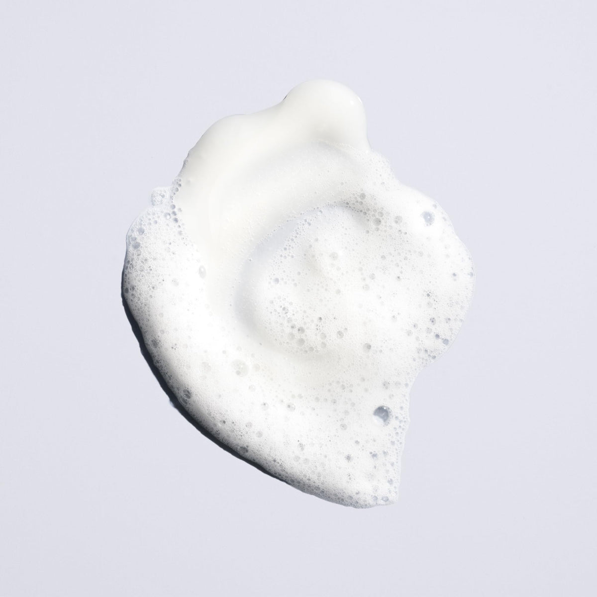 Hand holding Oribe Run-Through 8.5oz bottle to show size and travel-friendly scale