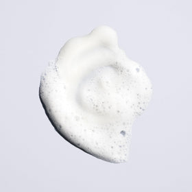 Hand holding Oribe Run-Through 8.5oz bottle to show size and travel-friendly scale