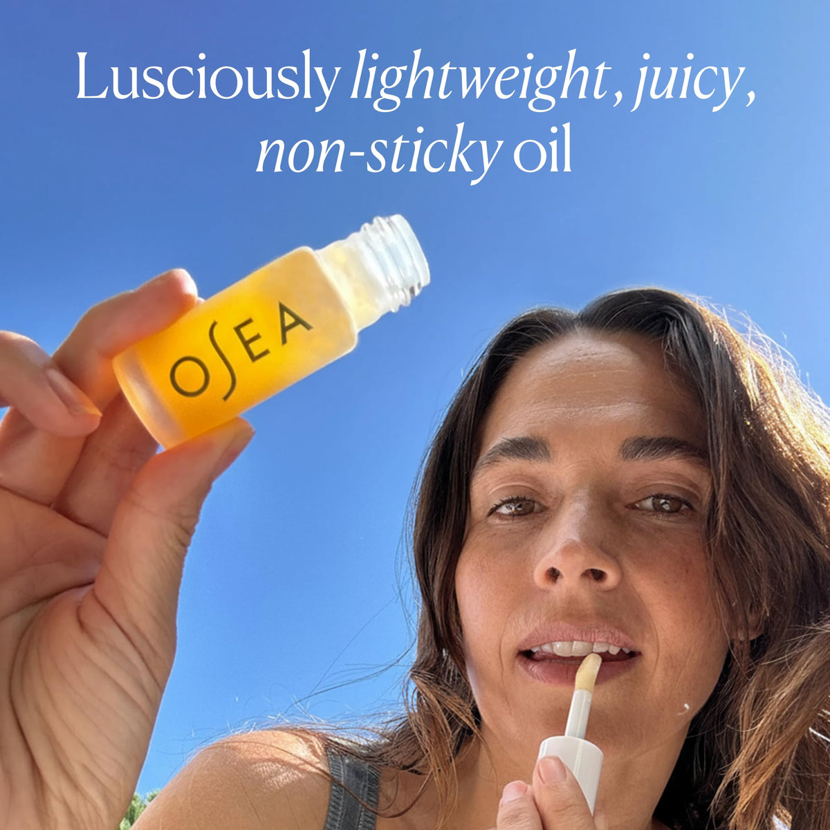 OSEA lip oil held in hand to show compact size and portability