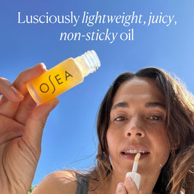 OSEA lip oil held in hand to show compact size and portability