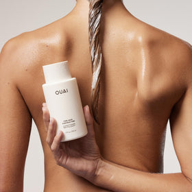 Pouring OUAI conditioner from refill to bottle demonstrating easy transfer and reduced waste
