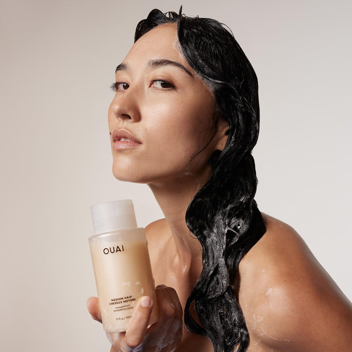 OUAI medium shampoo refill being poured into pump bottle for sustainability benefit