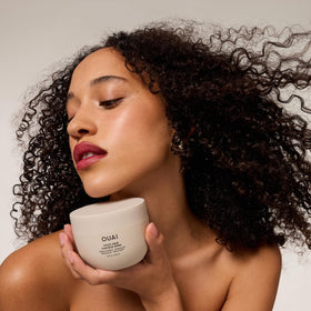 OUAI 3.4 oz tub next to a phone showing compact travel-friendly size and convenience